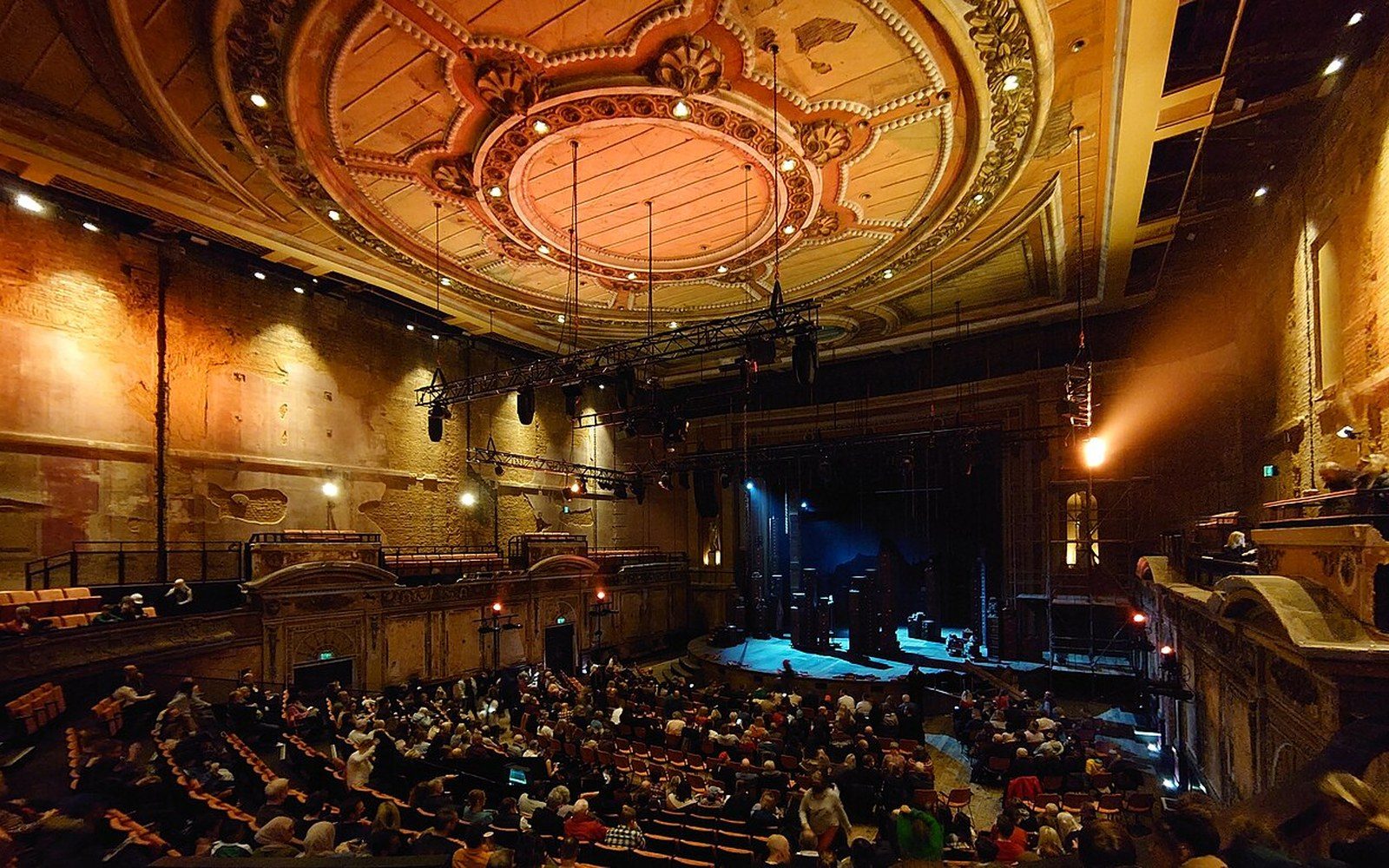 An empty auditorium photographed from the stage, house lights up, gilt and red plush