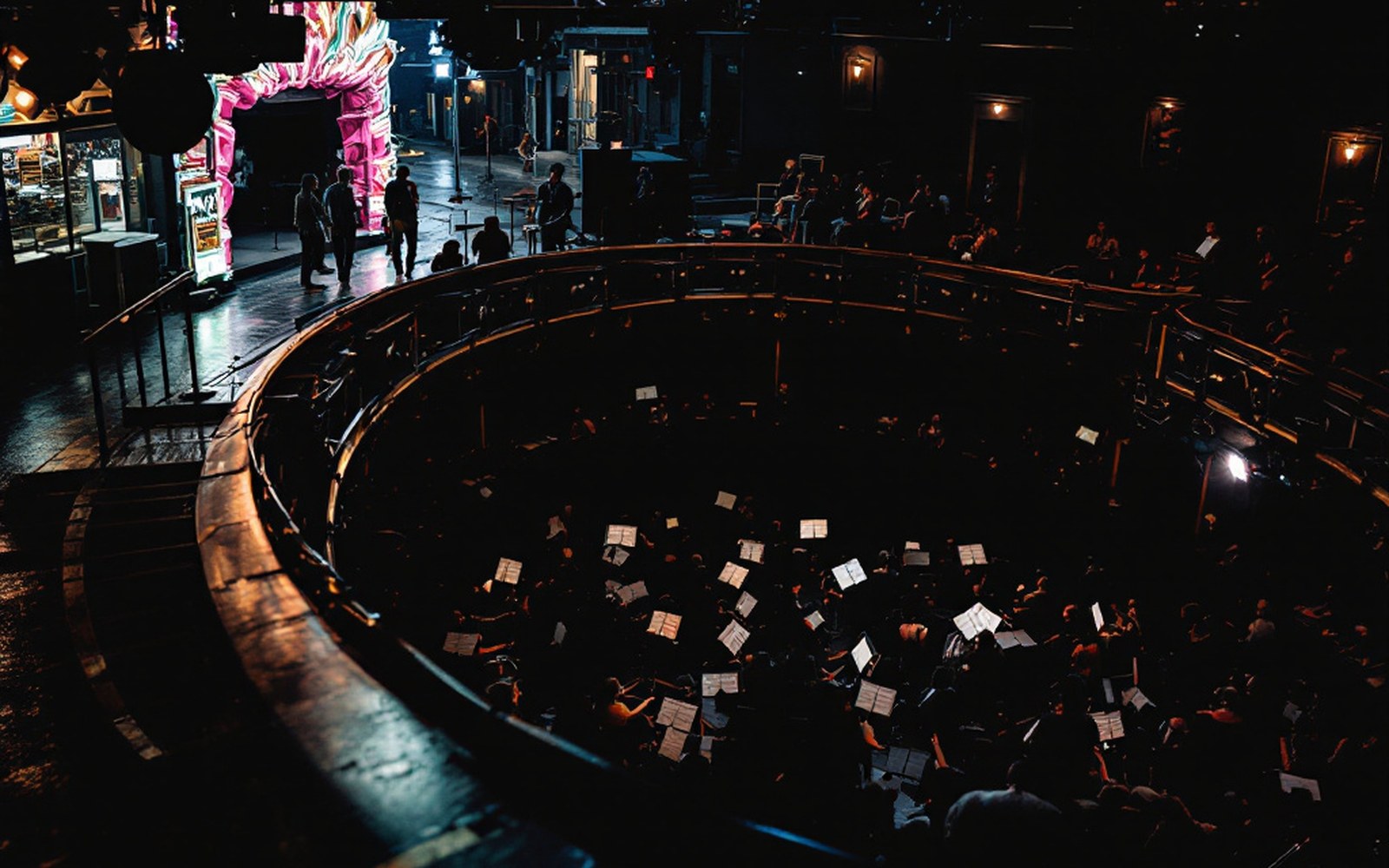 An orchestra pit at stage level, music stands packed shoulder to shoulder